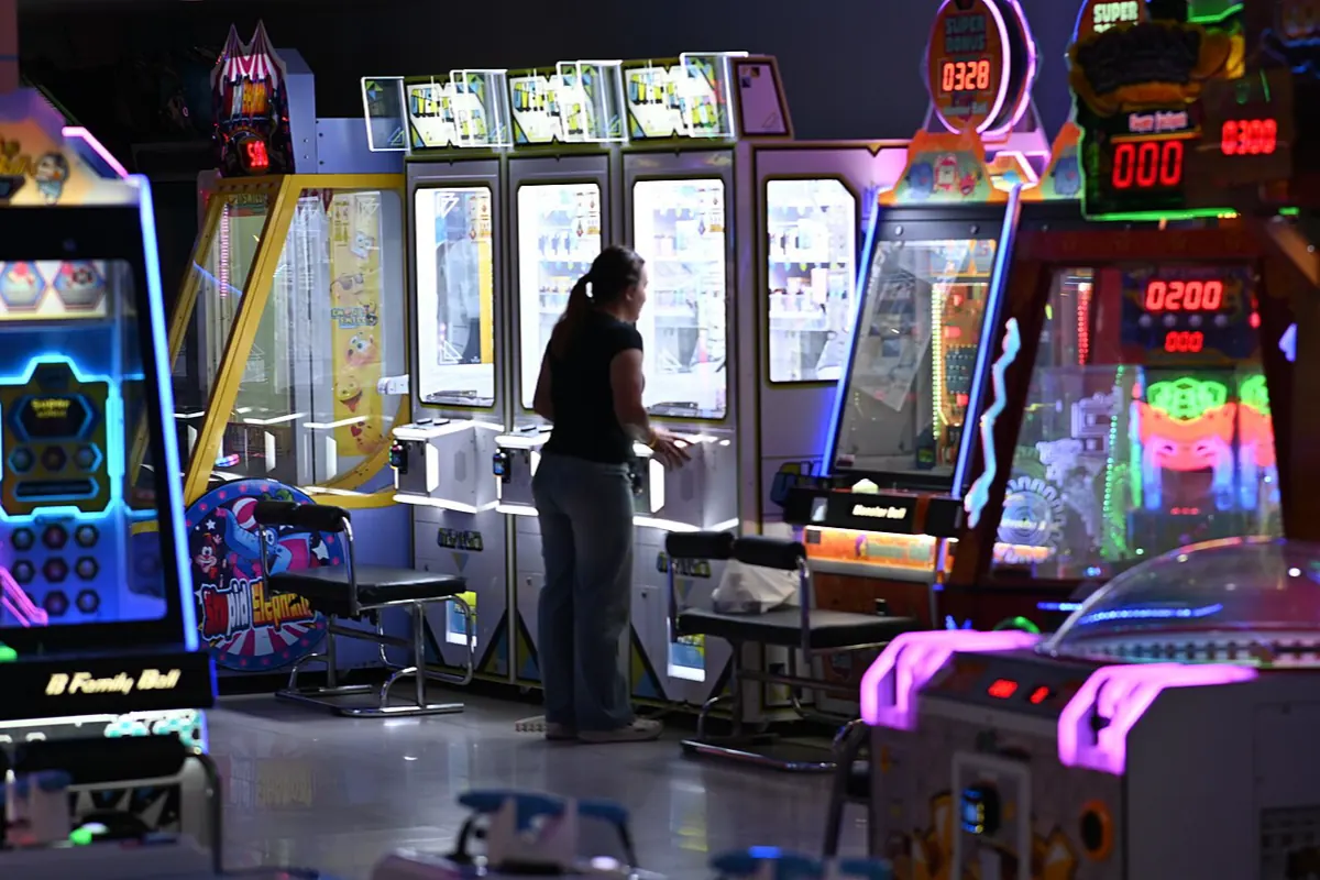 A dim arcade at night, lit by its cabinets